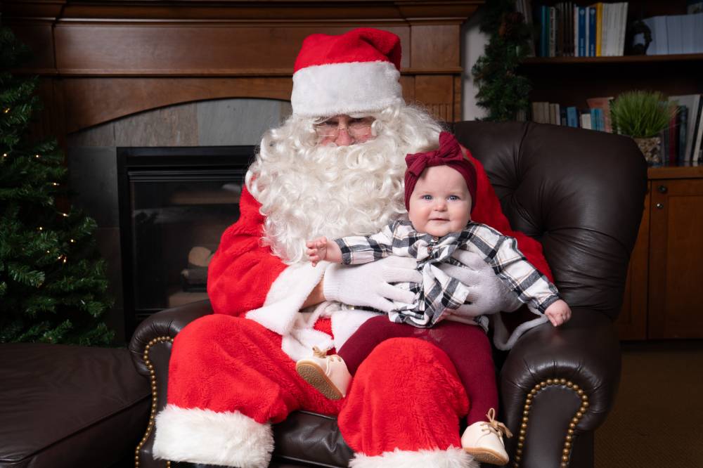 A baby sitting on Santa's lap.